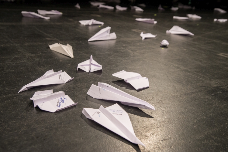 Foto von weißen Papierfliegern auf schwarzem Bühnenboden